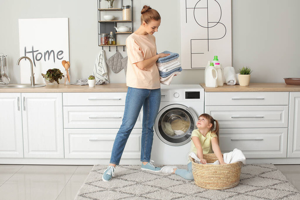 Woman and her cute little daughter doing laundry at home - 写真・画像