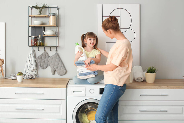 Woman and her cute little daughter doing laundry at home - Foto, imagen