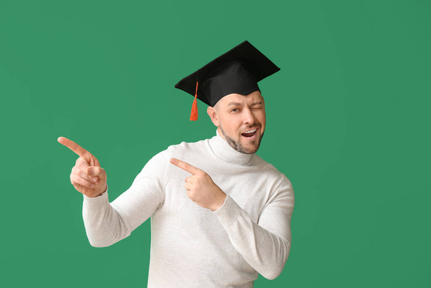 Человек в шляпе выпускника указывает на что-то на цветном фоне
 - Фото, изображение