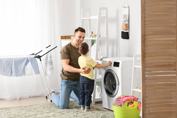 Homem e seu filho fazendo lavanderia em casa
 - Foto, Imagem