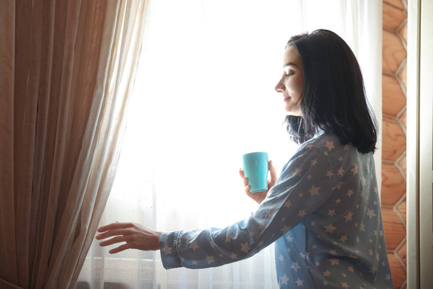 junge Frau mit Getränk am Fenster zu Hause. fauler Morgen - Foto, Bild