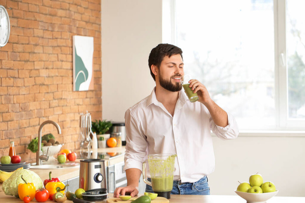 Mann trinkt gesunden hausgemachten Smoothie in Küche - Foto, Bild