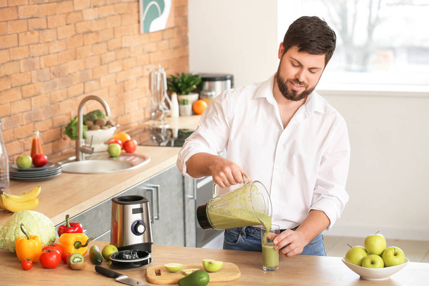 Man pouring healthy smoothie in glass at home - 写真・画像