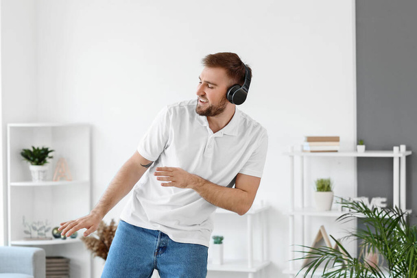 Handsome young man dancing and listening to music at home - 写真・画像