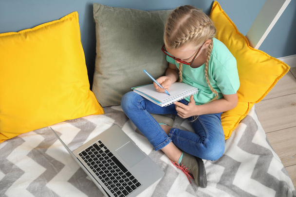 Nettes kleines Mädchen, das zu Hause lernt. Konzept der Online-Bildung - Foto, Bild
