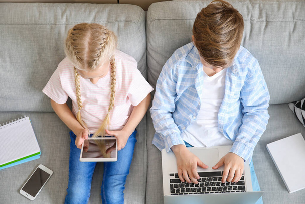 Evde dizüstü bilgisayarı ve tableti olan şirin çocuklar. Çevrimiçi eğitim kavramı - Fotoğraf, Görsel