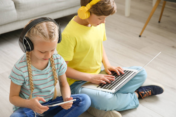 Crianças pequenas bonitos com laptop e tablet em casa. Conceito de educação online
 - Foto, Imagem