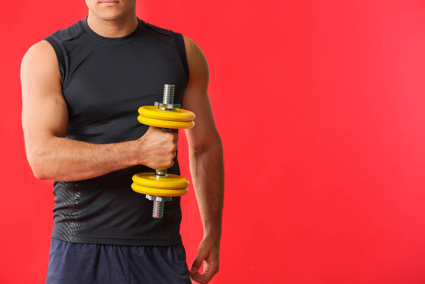 Sporty young man with dumbbell on color background - Foto, immagini