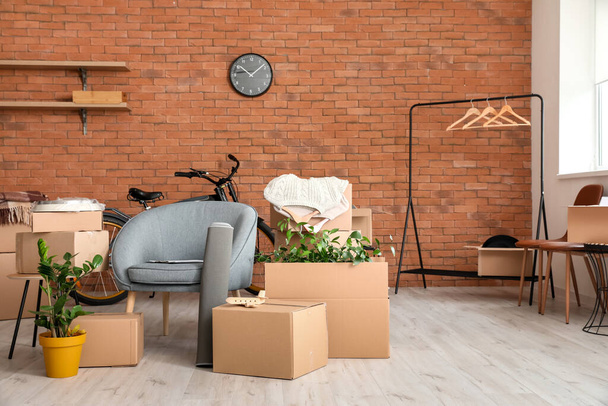Boîtes en carton avec effets personnels et fauteuil dans un nouvel appartement le jour du déménagement - Photo, image