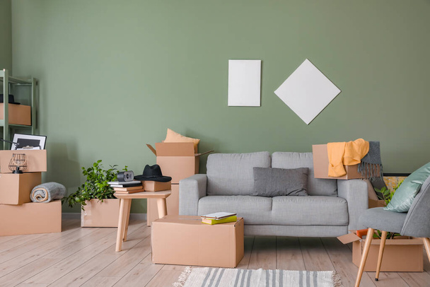 Картонні коробки з речами і диваном в новій квартирі в рухомий день
 - Фото, зображення