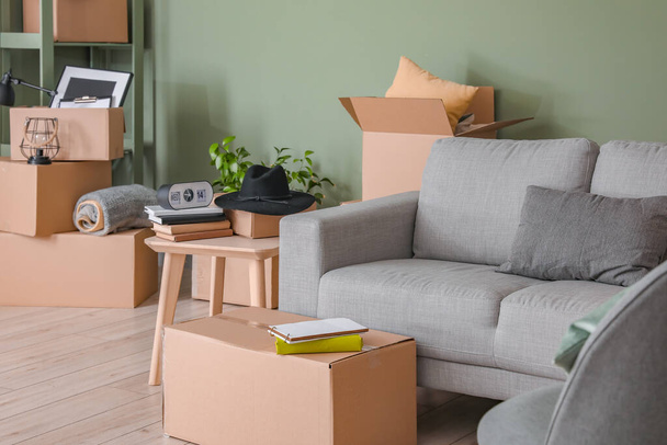 Pahvilaatikot, joissa on tavarat ja sohva uudessa asunnossa muuttopäivänä - Valokuva, kuva