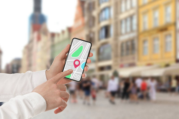 Man op zoek naar locatie met smartphone in de stad, close-up. Ruimte voor tekst  - Foto, afbeelding