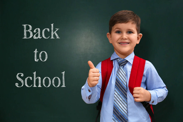 Cute little child near chalkboard with phrase BACK TO SCHOOL - Fotó, kép