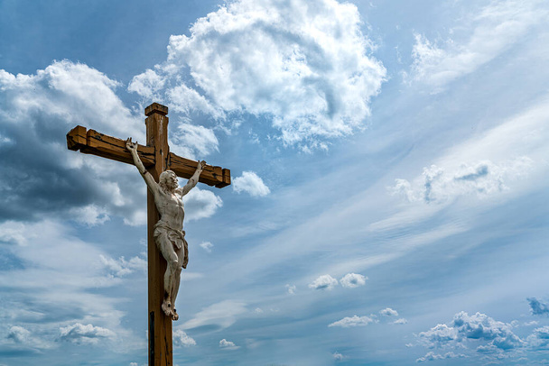 Concepto de crucifijo: Jesucristo en una cruz de madera, fondo dramático del cielo con nubes
 - Foto, imagen
