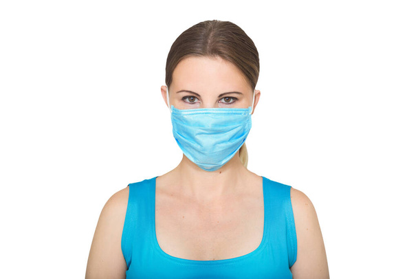 Studio portrait of young woman wearing face medical mask, looking at camera, close up, isolated white background. Flu epidemic, dust allergy, protection against virus - Fotó, kép