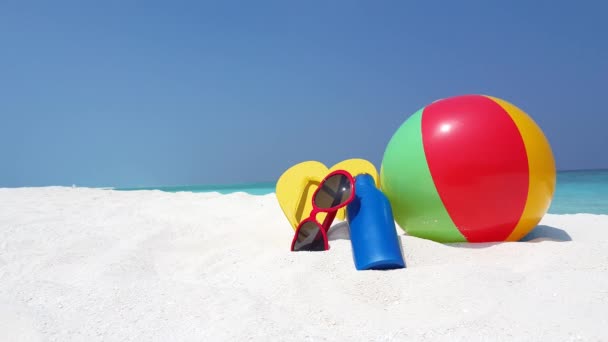 Aufblasbarer Ball mit Flip-Flops, Sonnenbrille und Flasche am Ufer. Sommerreise auf Bali. - Filmmaterial, Video