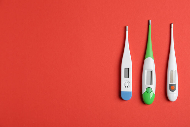 Modern digital thermometers on red background, flat lay. Space for text - Fotoğraf, Görsel