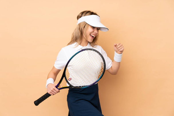 Nastoletnia Rosjanka odizolowana na beżowym tle gra w tenisa i świętuje zwycięstwo - Zdjęcie, obraz