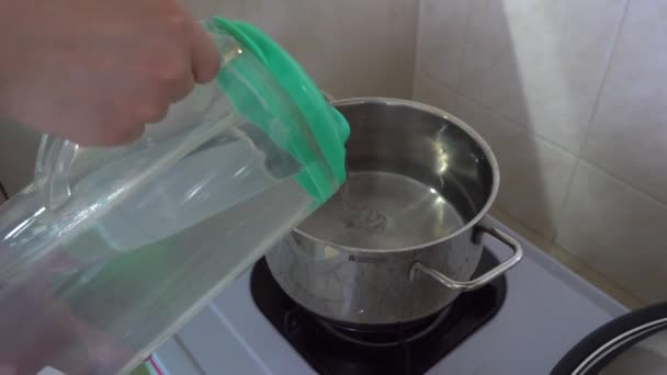 γυναίκα ρίχνει νερό μέσα στην κατσαρόλα μαγειρέματος - Πλάνα, βίντεο