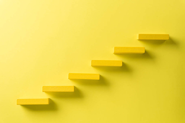 Concept de fondation du succès. Empilement de blocs de bois jaune comme escalier d'étape, succès dans le concept de croissance des entreprises sur fond de papier jaune
. - Photo, image