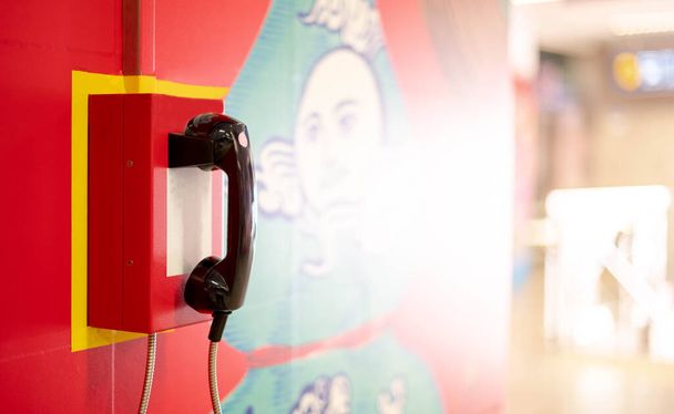 Czerwony telefon alarmowy na ścianie w ogólnodostępnym obszarze metra podziemny dworzec kolejowy, koncepcja sytuacji alarmowej wywołującej potrzebę kontaktu z ludźmi w pilnych działaniach. - Zdjęcie, obraz
