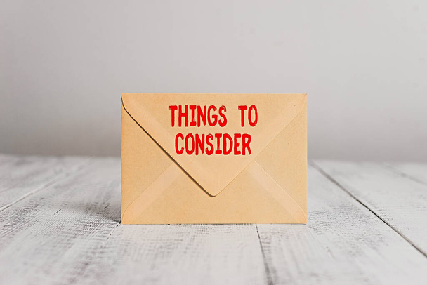 Handwriting text writing Things To Consider. Concept meaning think about carefully especially in making decisions Closed standing rectangular colored envelope old wooden vintage background. - Photo, Image