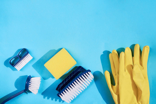 Blue dish brushes and yellow gloves and sponge on a blue background. Space for text - Φωτογραφία, εικόνα