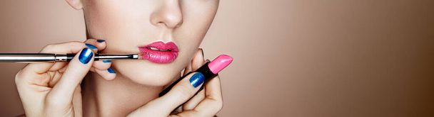 Makeup artist applies lipstick. Beautiful woman face. Makeup detail. Beauty girl with perfect skin. Lips and nails manicure - Photo, image