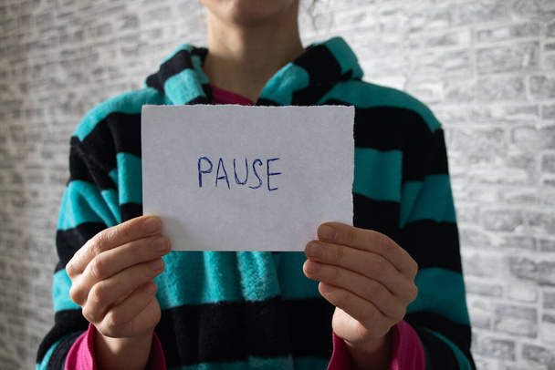слово "пауза" пишеться на аркуші паперу, який тримає карантинна дівчина
 - Фото, зображення