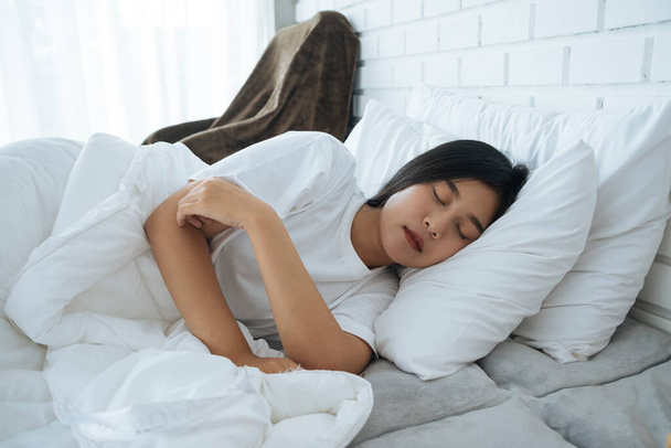 Χαριτωμένο κορίτσι Thai κοιμάται σε ένα λευκό κρεβάτι. - Φωτογραφία, εικόνα