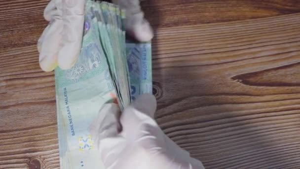Жіночі руки з медичними рукавичками обчислюють банкноти Малайзії. Фінансова концепція, концепція бухгалтерського обліку. - Кадри, відео