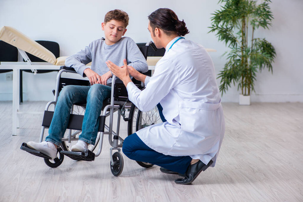 Giovane medico maschio pediatra e ragazzo in sedia a rotelle
 - Foto, immagini