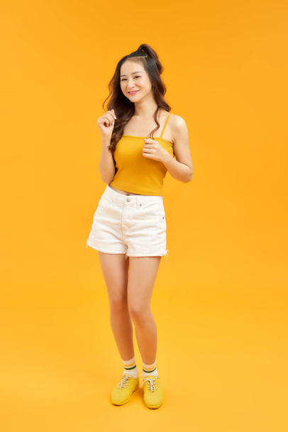 Cheerful young asian woman girl in yellow crop top posing isolated on yellow background.  - Foto, Imagen