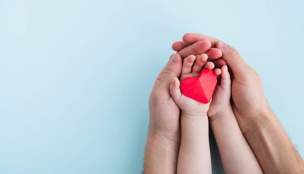 Υγεία και ιατρική έννοια. Άντρας και παιδί κρατούν κόκκινη καρδιά σε γαλάζιο φόντο. Πάνω όψη, αντιγραφή χώρου - Φωτογραφία, εικόνα
