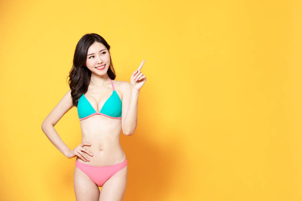 asian woman is relaxed and carefree with bikini swimsuit and point to copyspace - Fotografie, Obrázek