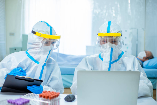 doctors discuss patient situation on computer with the isolation gown or protective suits and surgical face masks - Fotoğraf, Görsel