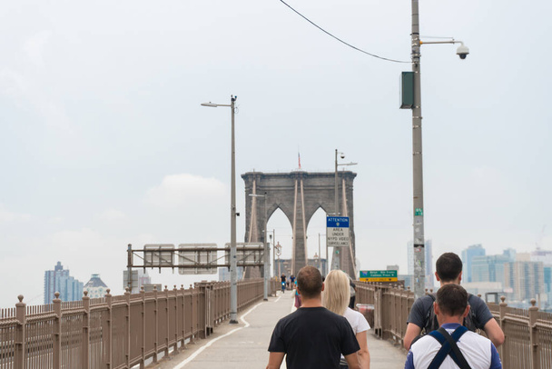 New York City, USA - August 6, 2019:People walk across the famous Brooklyn Bridge during a cloudy day. - Valokuva, kuva