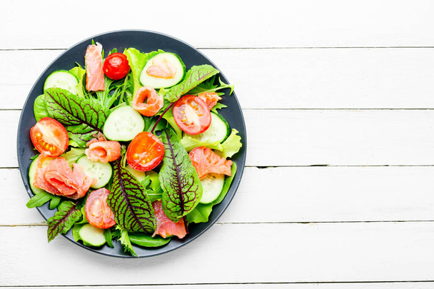 Étvágygerjesztő saláta lazaccal, zöldségekkel és gyógynövényekkel. - Fotó, kép