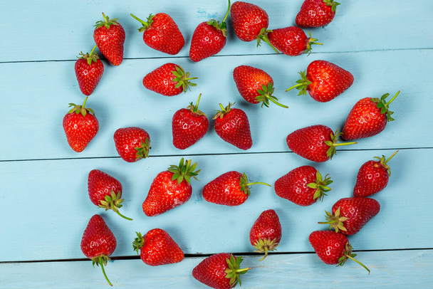 Ripe red strawberries on a blue wooden background - Zdjęcie, obraz