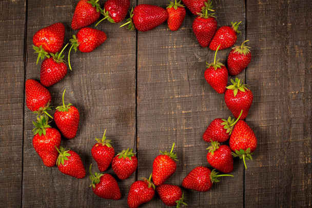 Ripe red strawberries on a brown wooden background - Zdjęcie, obraz