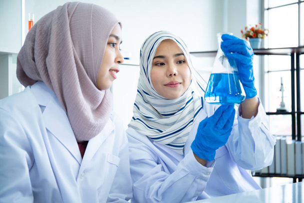Asyalı genç Müslüman bilim adamı hastane laboratuvarında kimyasal deneyi test ediyor. Laboratuvarda araştırma yapan ve deney yapan profesyonel bir kimyager.. - Fotoğraf, Görsel