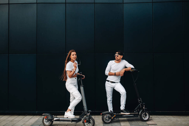 Dziewczyna i facet chodzą na skuterach elektrycznych po mieście, para zakochana w skuterach - Zdjęcie, obraz