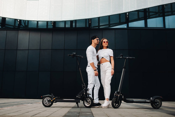 A girl and a guy are walking on electric scooters around the city, a couple in love on scooters - Photo, image
