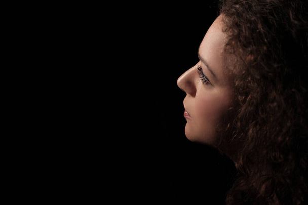 retrato de una hermosa joven con el pelo rizado sobre fondo oscuro
 - Foto, Imagen