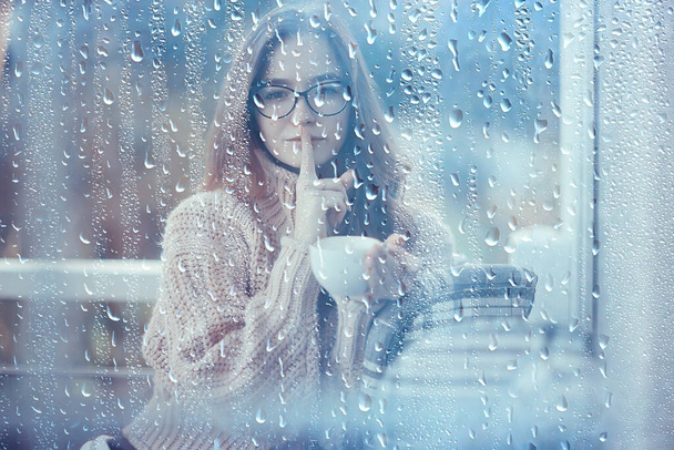 syksyllä kahvia sateisena päivänä, tyttö lasin takana kupin kuumaa kahvia
 - Valokuva, kuva