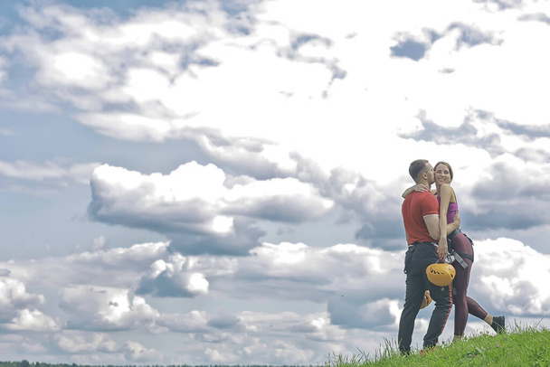 love couple in helmets outdoor activities nature, rope climbing park, against the sky - Photo, image