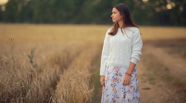 young brunette in summer with long hair in a field, happy person health beauty posing at sunset - 写真・画像