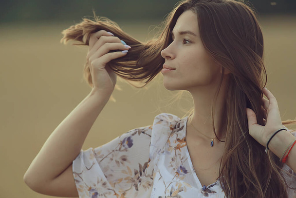 young brunette in summer with long hair in a field, happy person health beauty posing at sunset - Foto, immagini