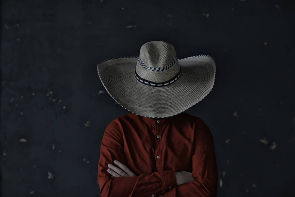 άνθρωπος σε ένα καπέλο με αχυρένιο χείλος, κρύβει το πρόσωπό του, ινκόγκνιτο τύπος, αφηρημένη κάντρι μουσική στυλ Αμερική δυτικά - Φωτογραφία, εικόνα