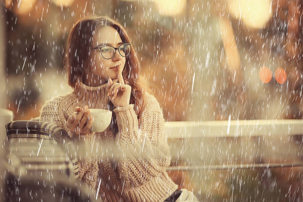 autumn coffee on a rainy day, girl behind a glass with a cup of hot coffee - Foto, imagen
